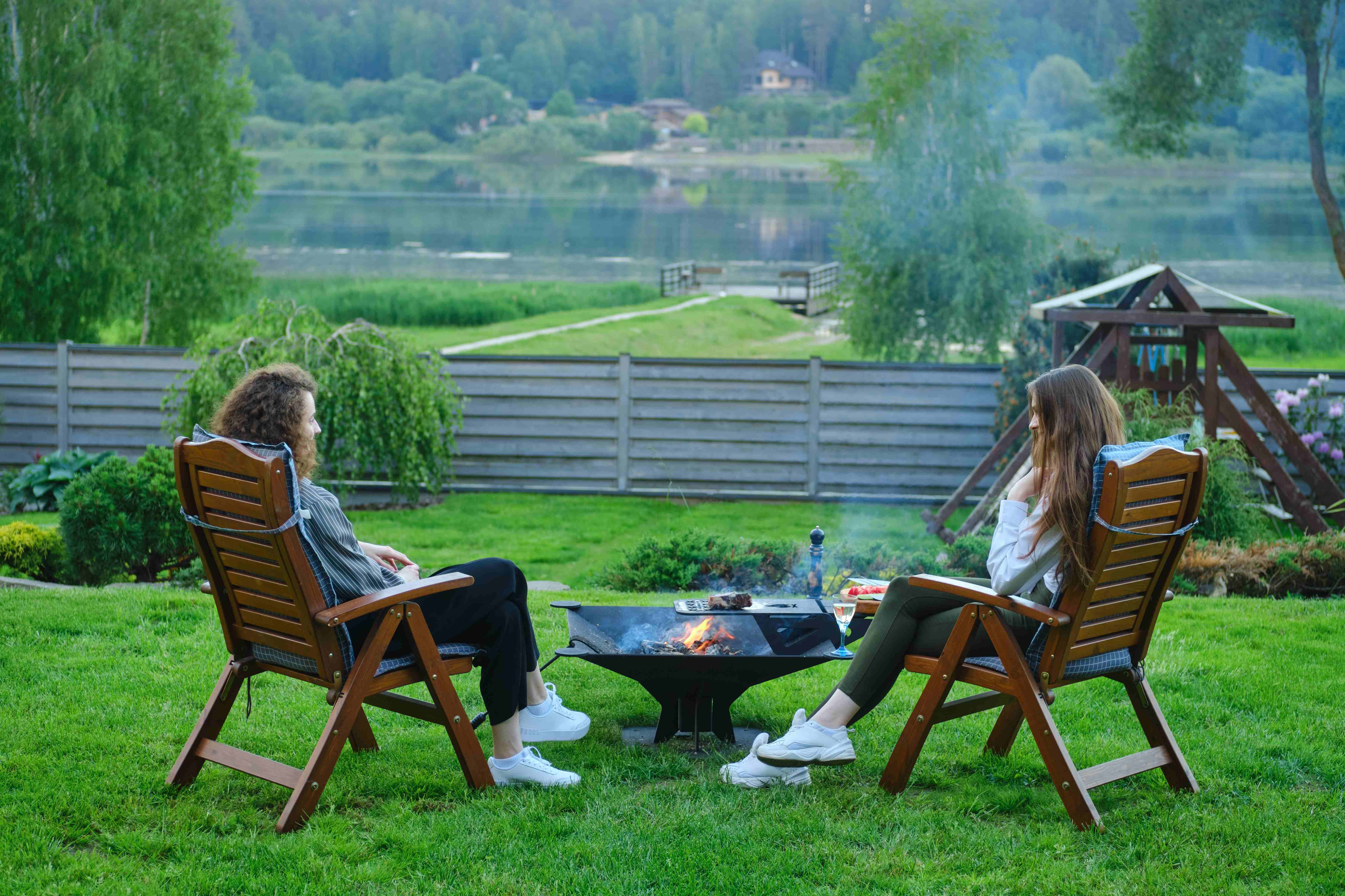 Two friends gathered around a fire pit in the backyard during a summer barbecue