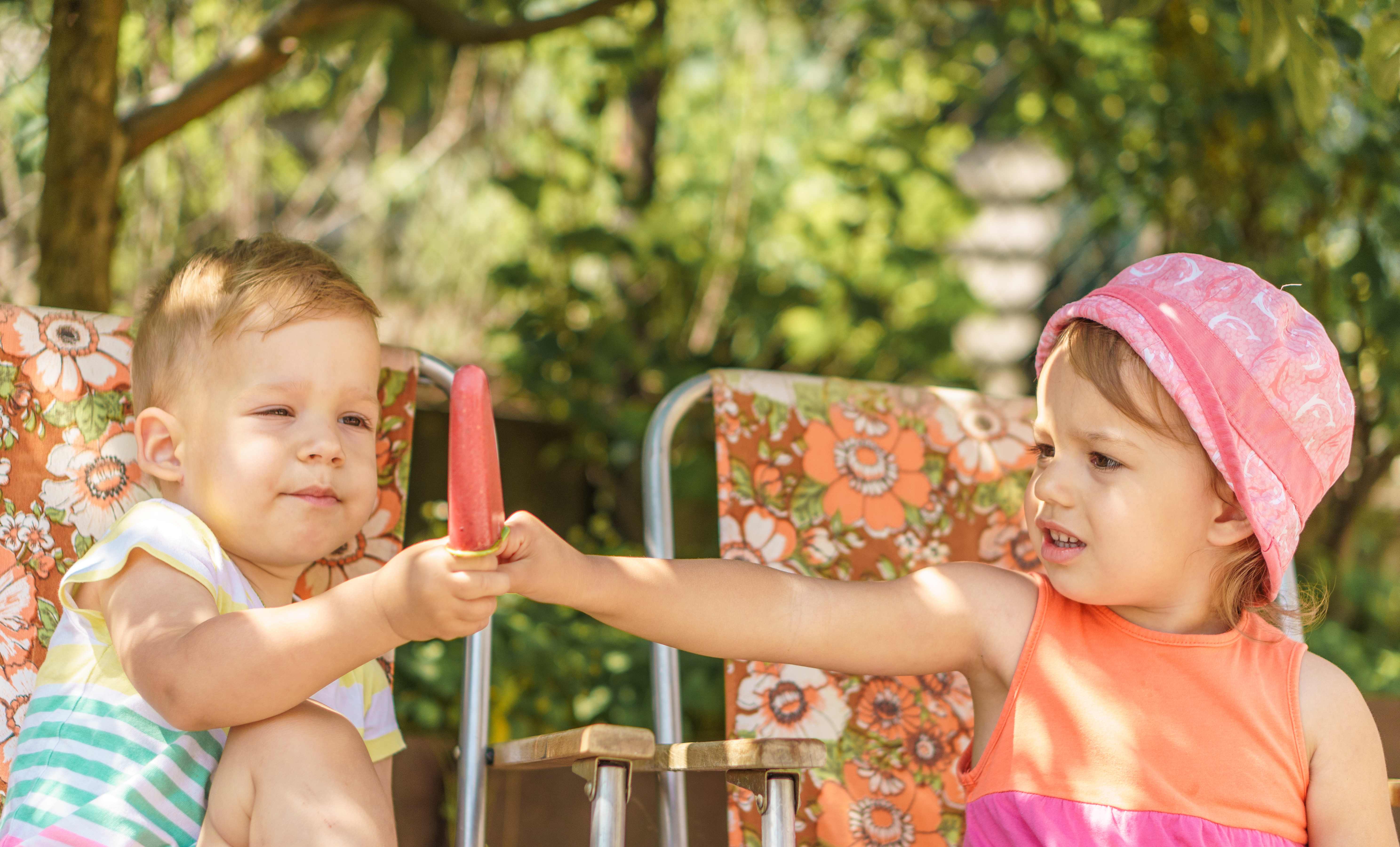 Two toddlers share a homemade popsicle before the end of summer