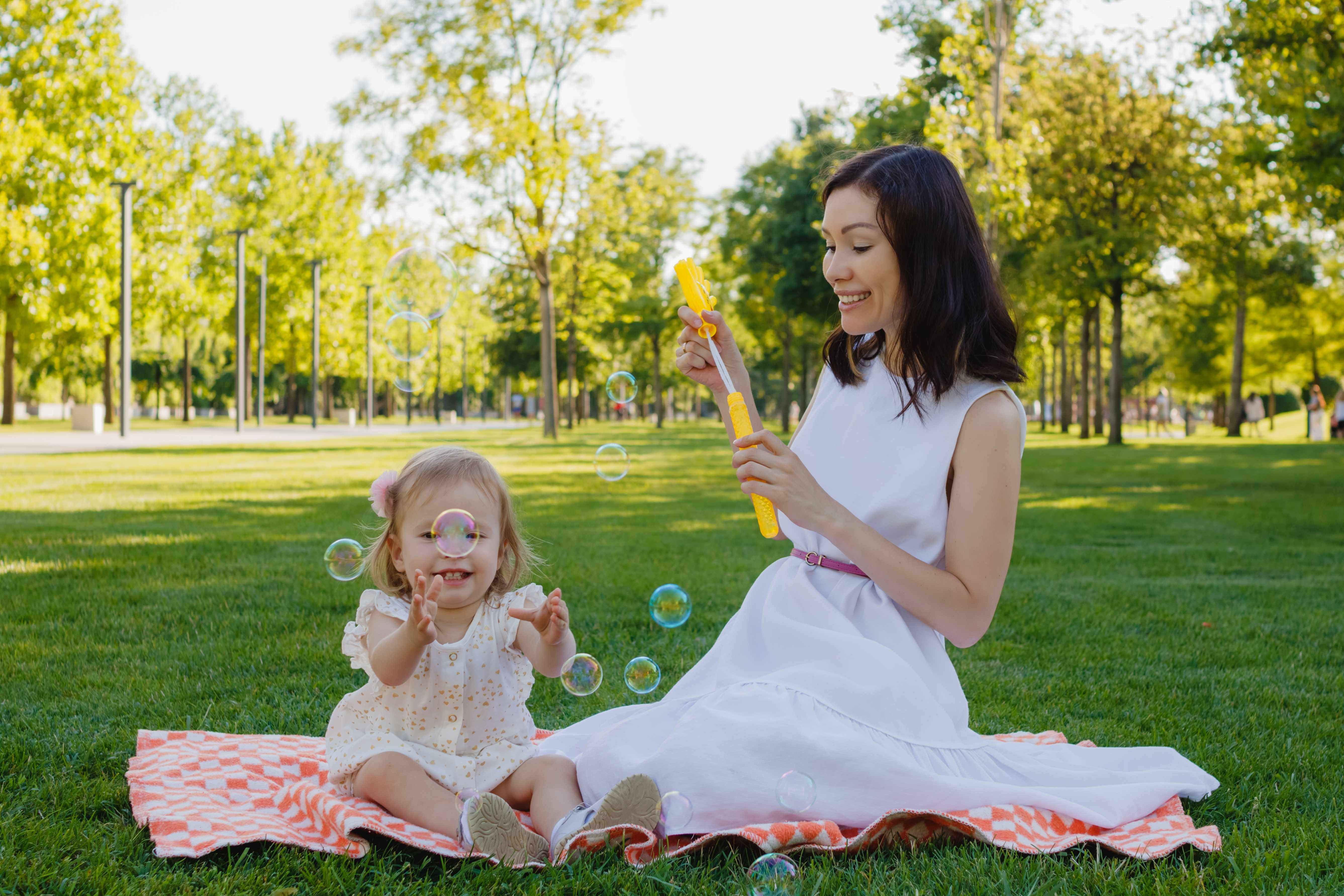 A family spends time together at a park blowing bubbles and enjoying summer 