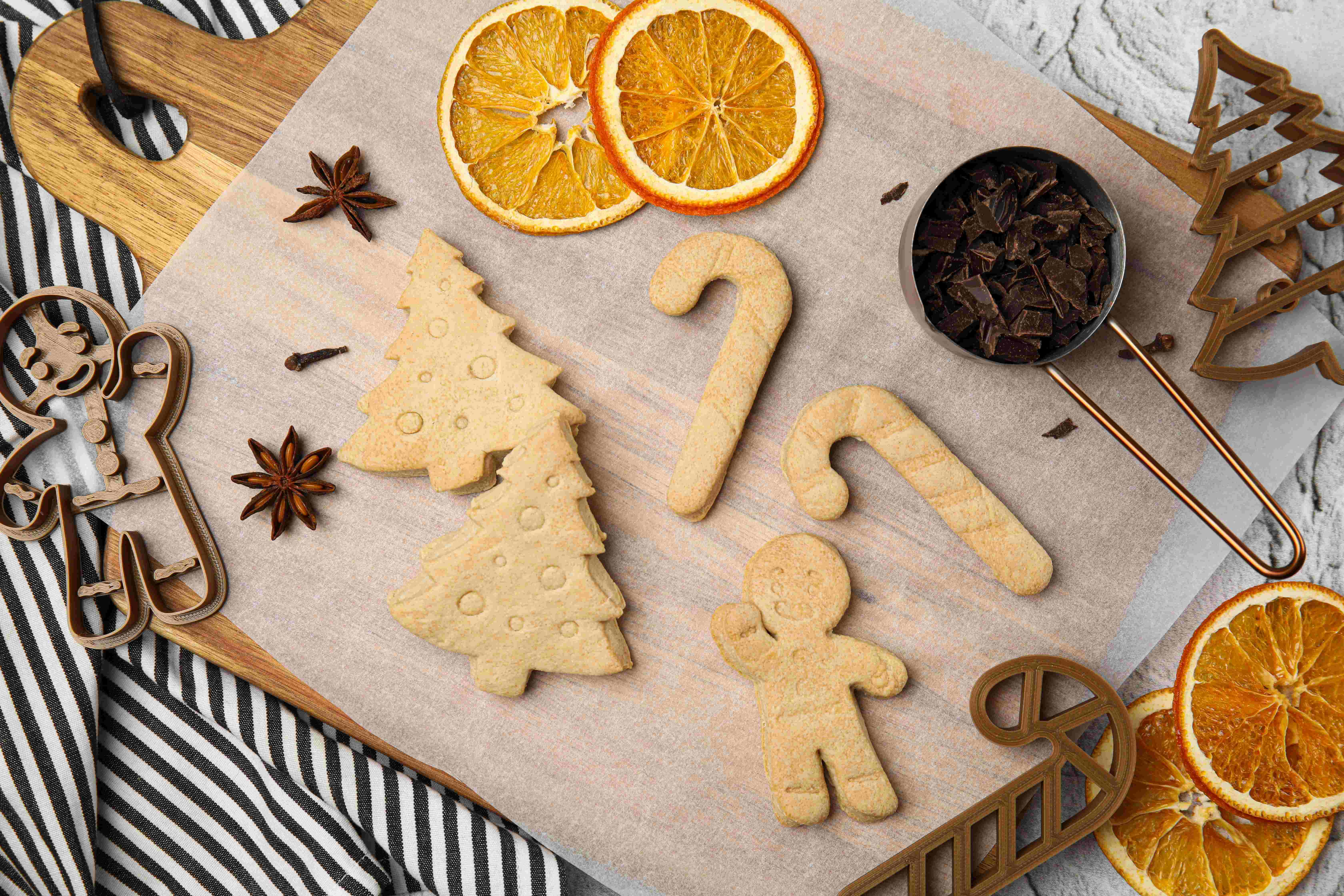 Cookie dough cut into festive shapes with holiday-themed cookie cutters
