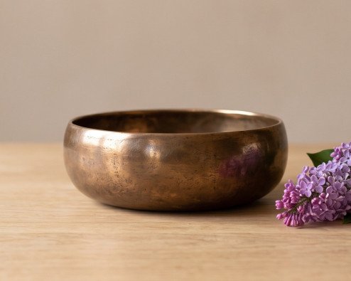 Cast bronze bowl and a sprig of lilac on an oak table, the traditional 8 year anniversary gift