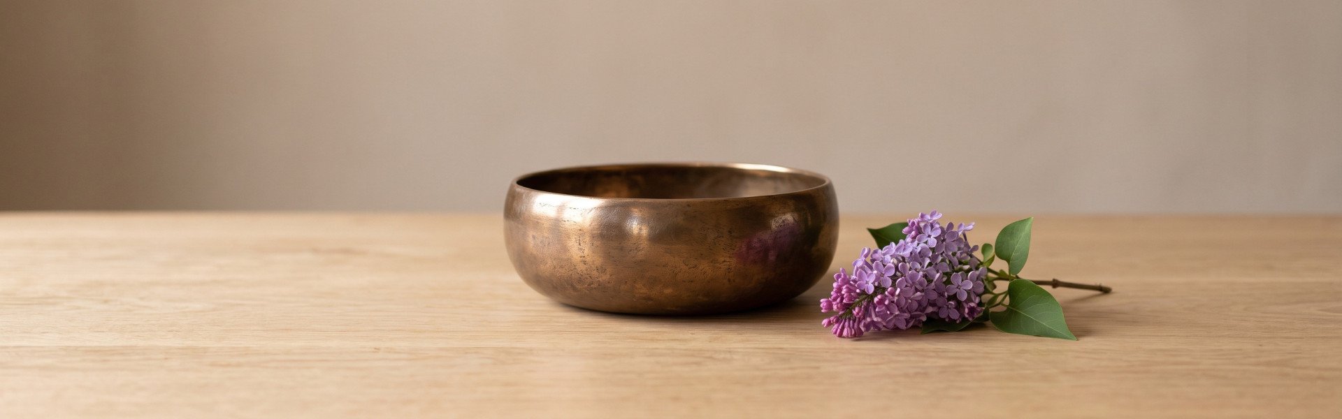 Cast bronze bowl and a sprig of lilac on an oak table, the traditional 8 year anniversary gift