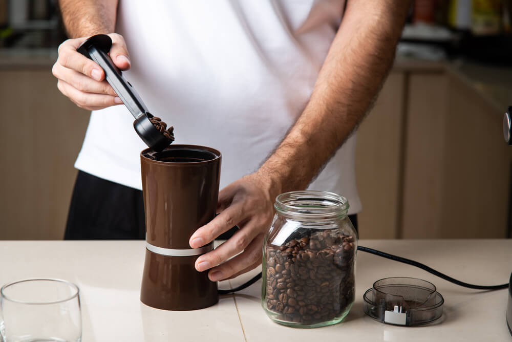A coffee lover uses the grinder he got as a gift from his partner.