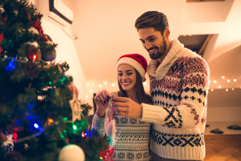 A married couple hangs a personalized Christmas ornament with their photo inside.