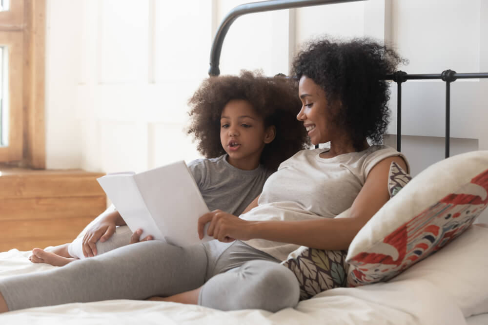 A mom and daughter wear cozy leggings in bed on a chilly fall day.