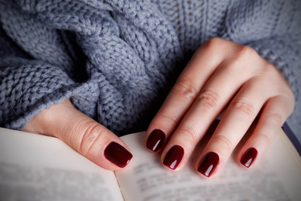 A stylish woman wears warm nail polish colors for autumn.