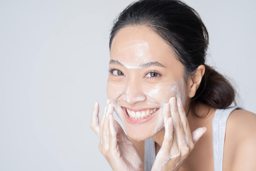 A woman practices self-care by applying moisturizer before bed.