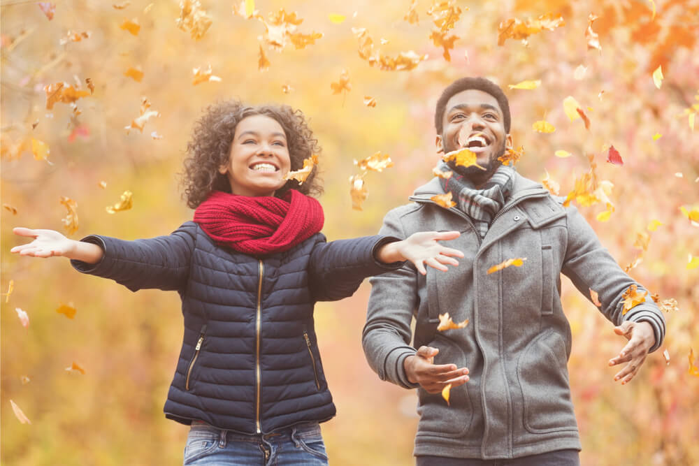 A couple has fun playing in the leaves on an autumn day. 