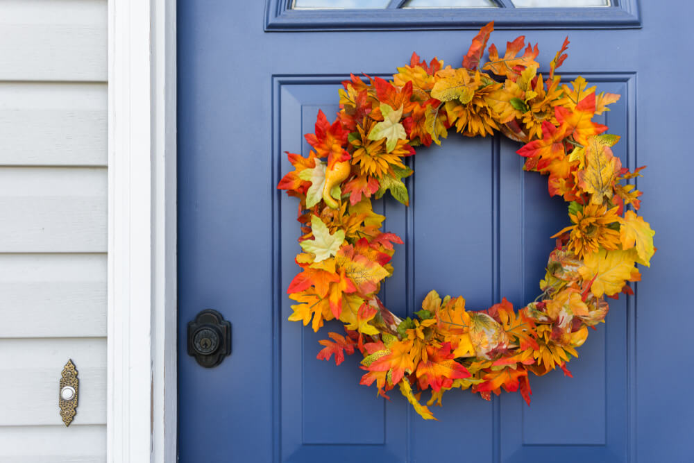 A colorful autumn wreath hangs on the front door for fall.
