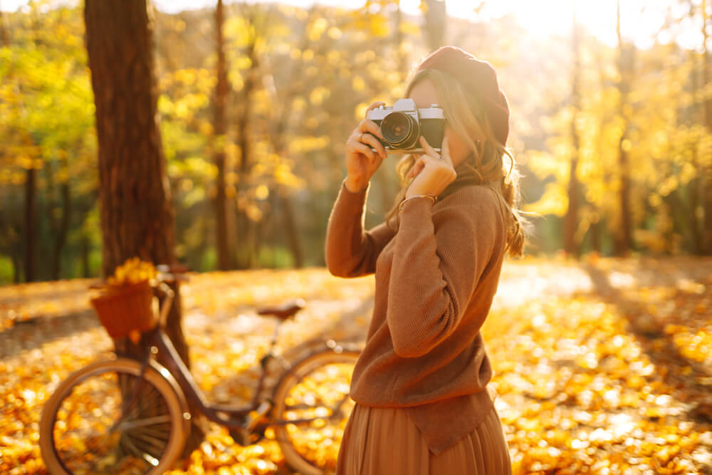 A woman takes pictures outdoors on a beautiful autumn day.