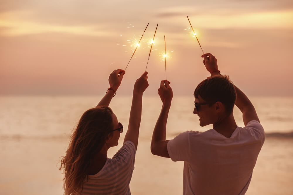 A couple enjoys one of the last days of summer by lighting sparklers at the beach.