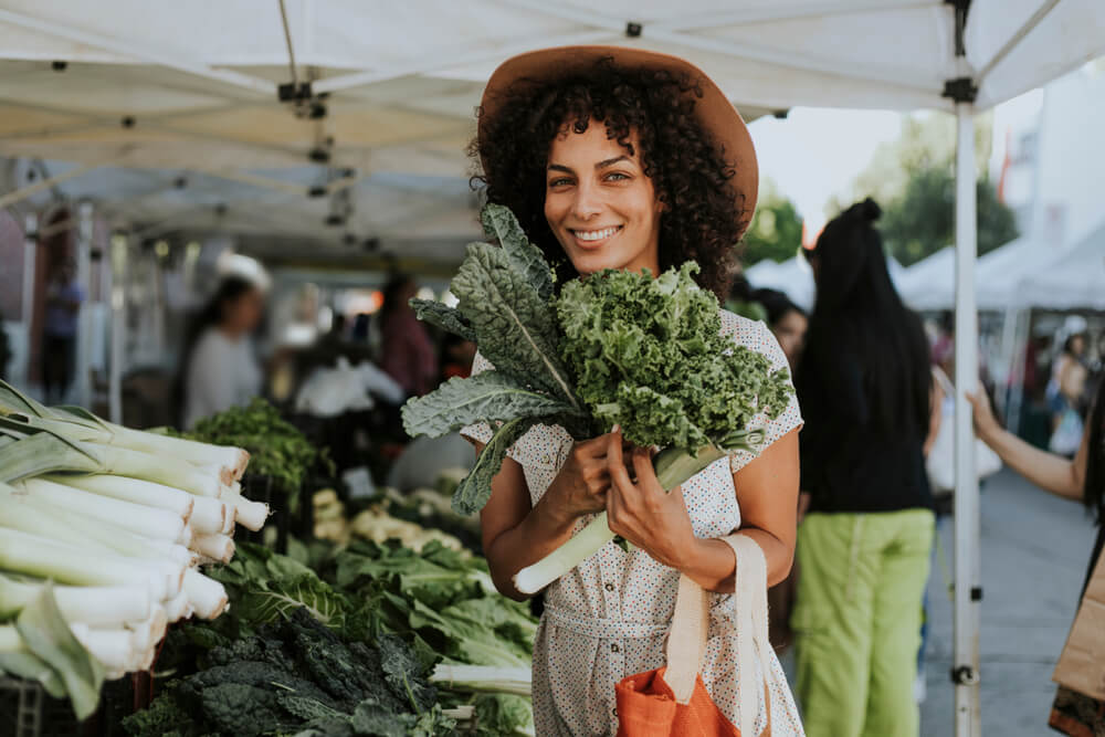 A woman shops for fresh vegetables at a local farmer’s market during the summer.