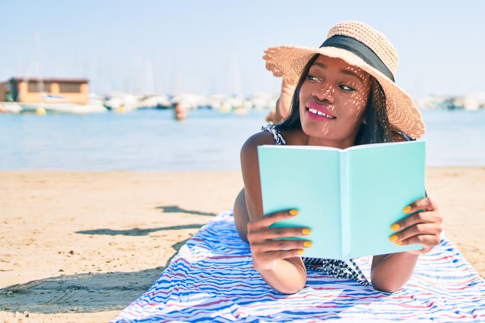 A young mom relaxes on the beach with a book during the family vacation.