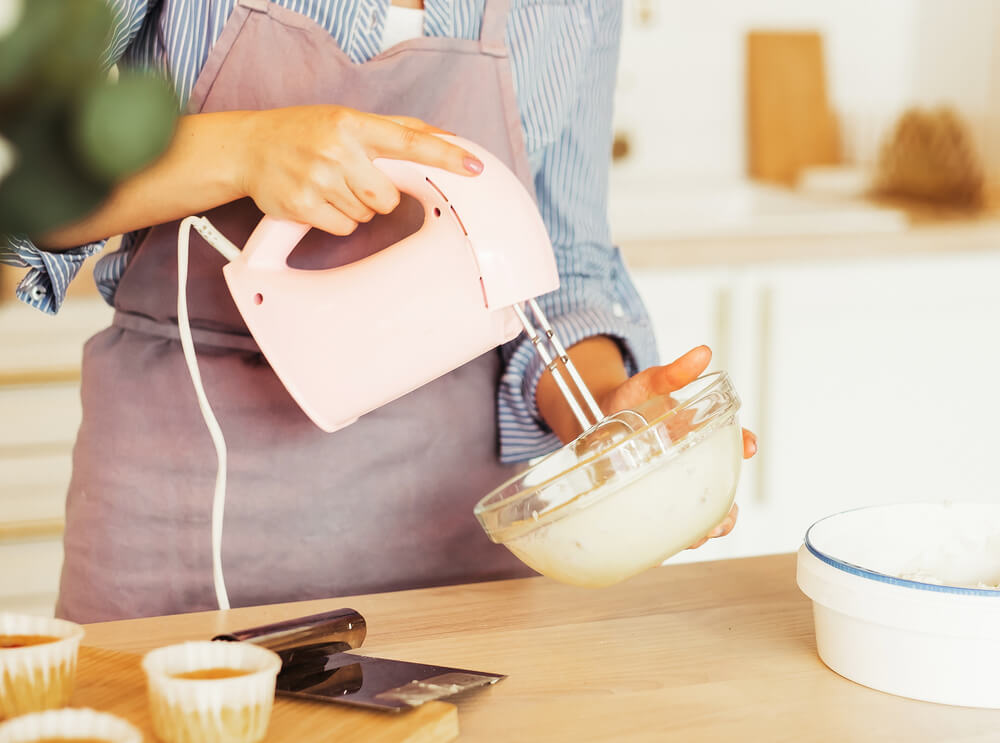 A woman bakes a delicious birthday cake using an electric mixer.