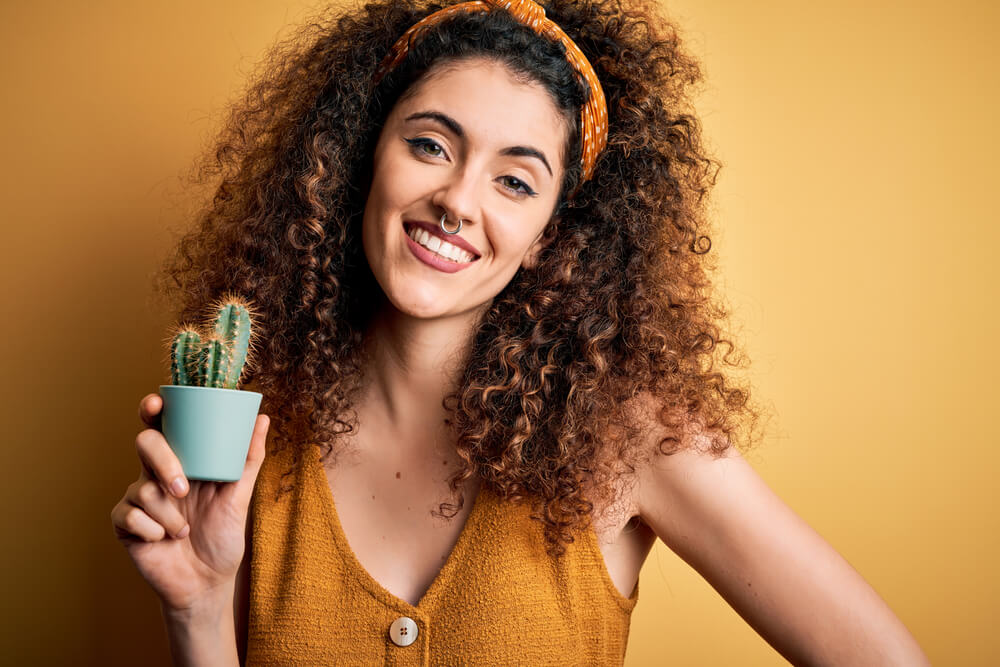 An alternative woman is excited to receive a small cactus as a gift from a friend.