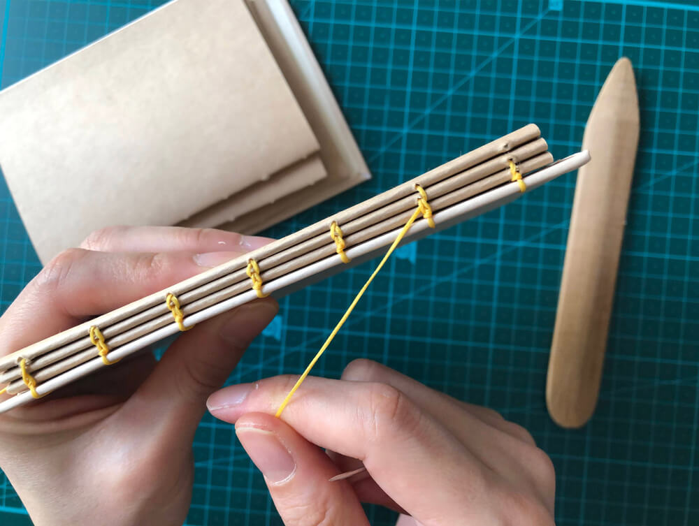 A creative woman learns a new DIY skill with a bookbinding kit.
