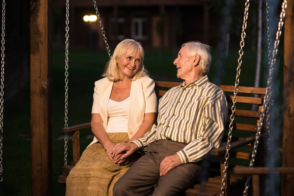 A senior couple spends a romantic evening together on a porch swing.