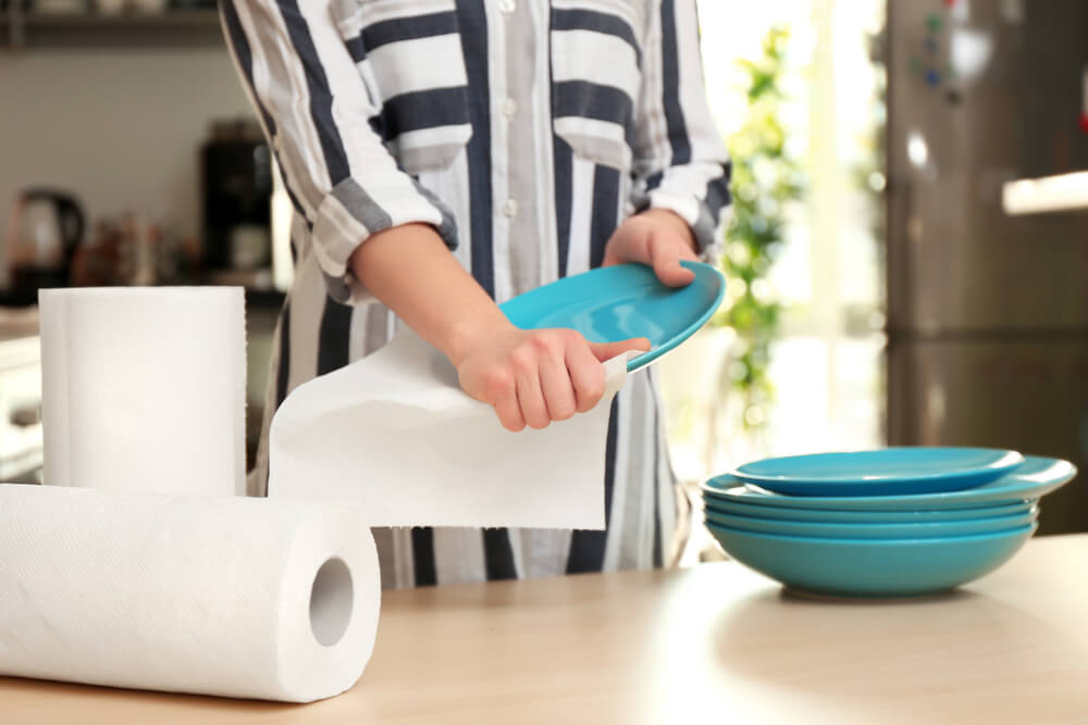 An environmentally conscious woman dries her dishes with reusable paper towels.