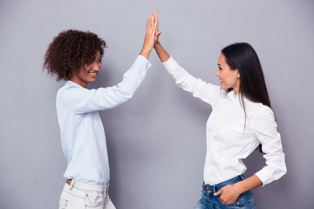 Two supportive friends encourage each other with a high-five.