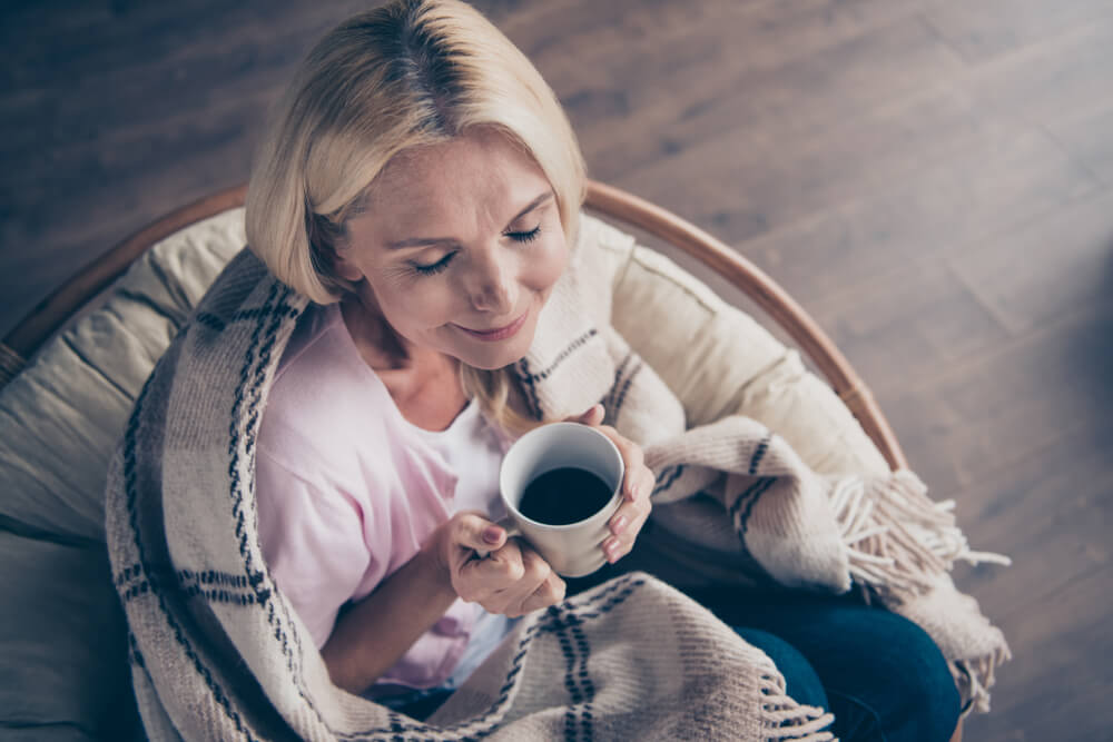 An older mom enjoys a hot cup of coffee in the morning.