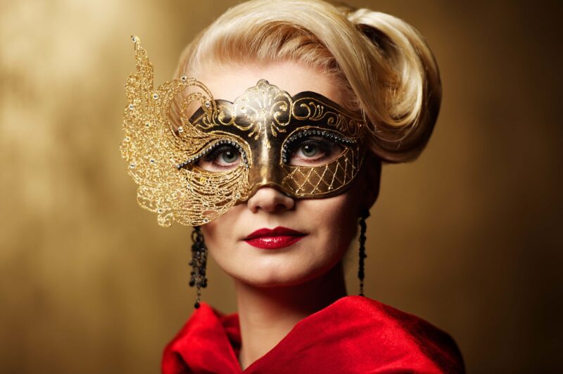 An elegant woman wears a mask to attend a masquerade ball. 