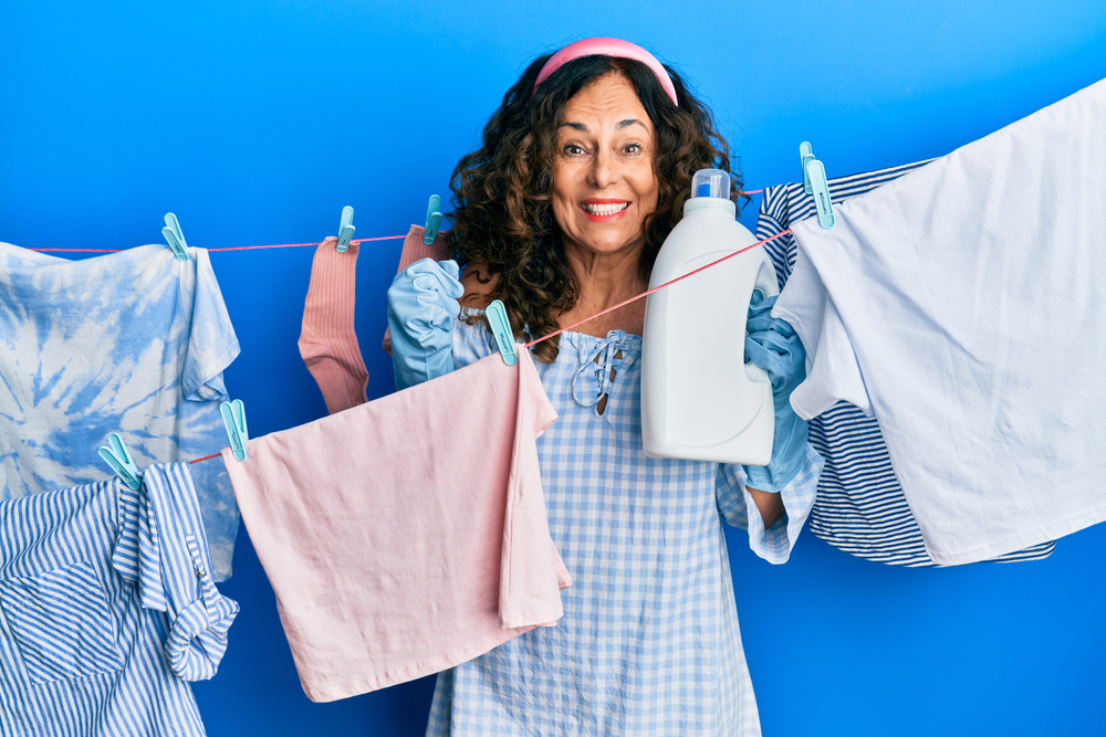 An older woman who lives by herself does a load of laundry.