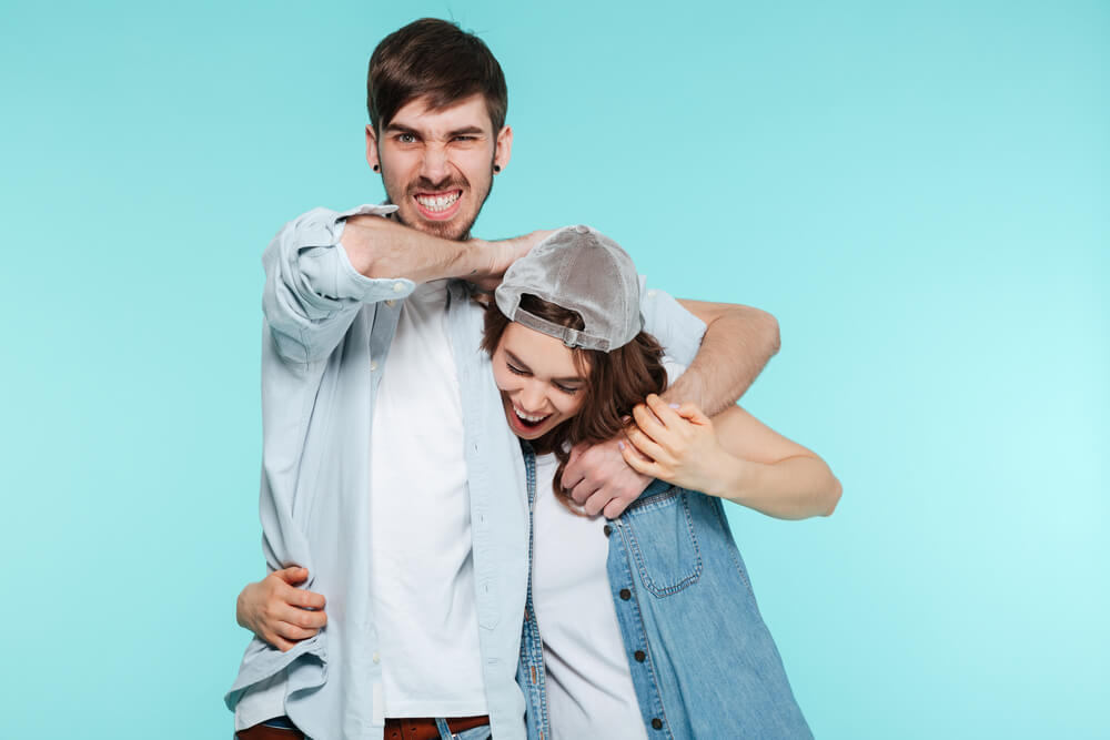 A loving older brother teases his sister by putting her in a playful headlock.