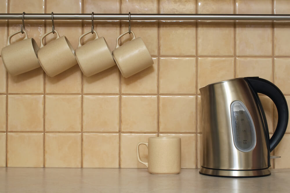 An organized kitchen with matching mugs arranged on a hanging rack.