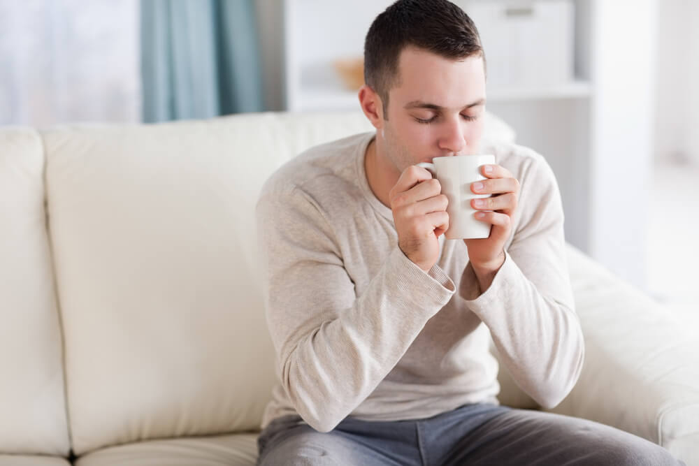 A man relaxes at home with a soothing cup of herbal tea.