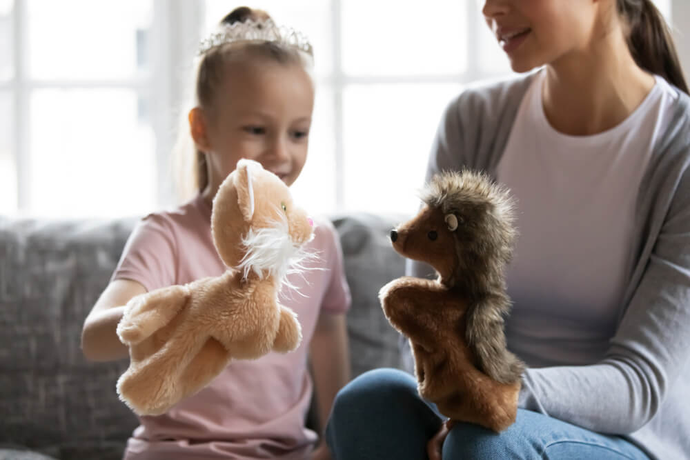 A babysitter helps a single mom by entertaining her daughter with hand puppets.