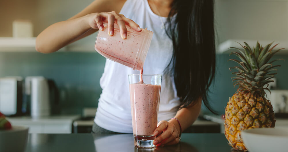 A healthy mom pours herself a smoothie from her single-serve blender.