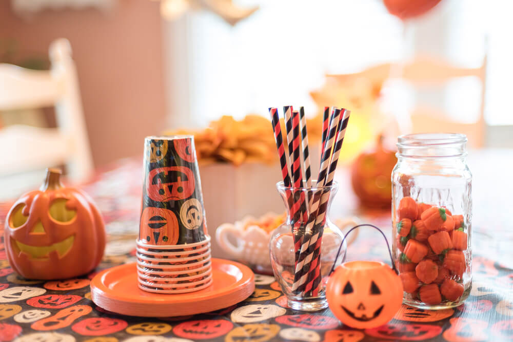 Pumpkin-themed cups, plates, and decorations for a Halloween baby shower.