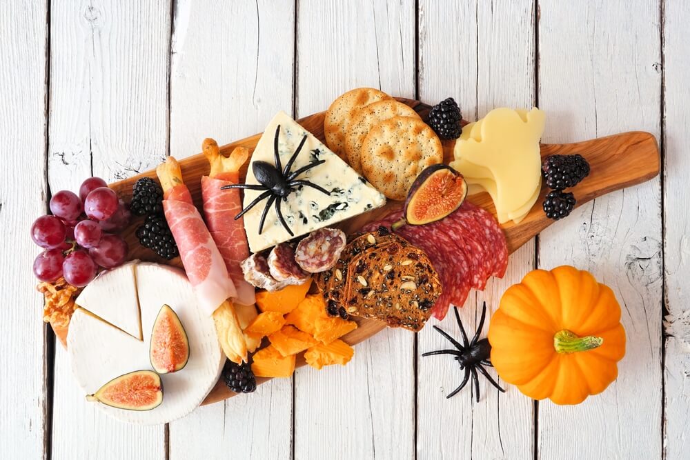 A charcuterie board decorated for a baby shower with a Halloween theme.