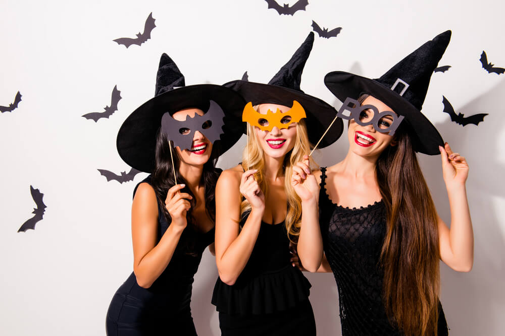 Three friends dressed in costumes for Halloween celebrating in October.