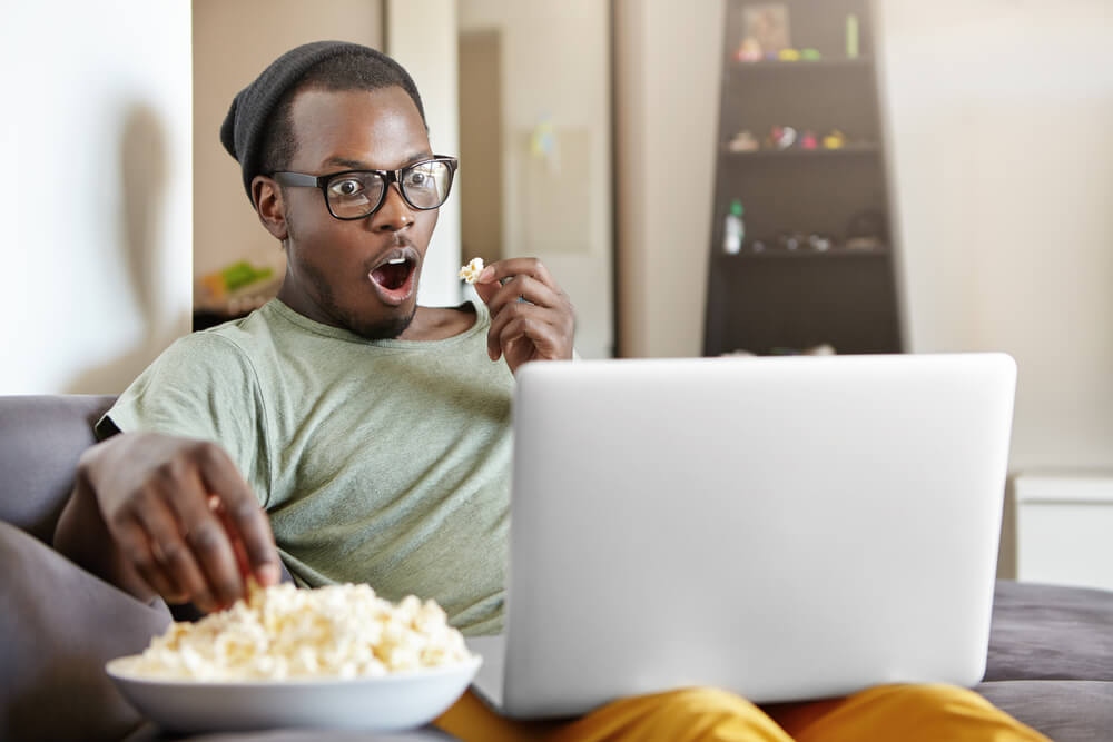 A movie lover enjoys a film on his laptop using a streaming service.