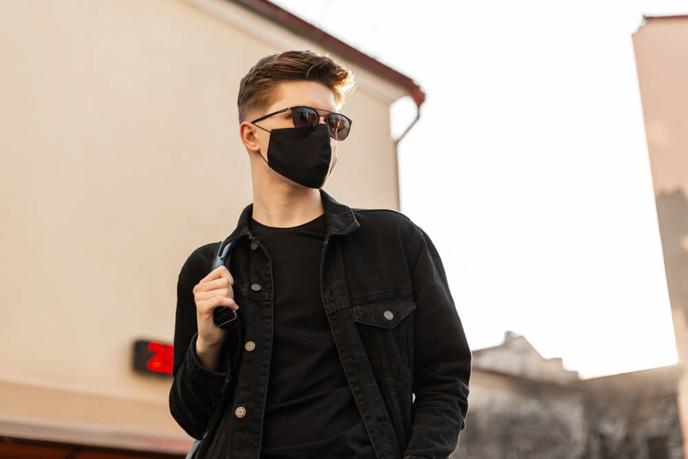 A cool boyfriend wears a black face mask that matches his outfit. 