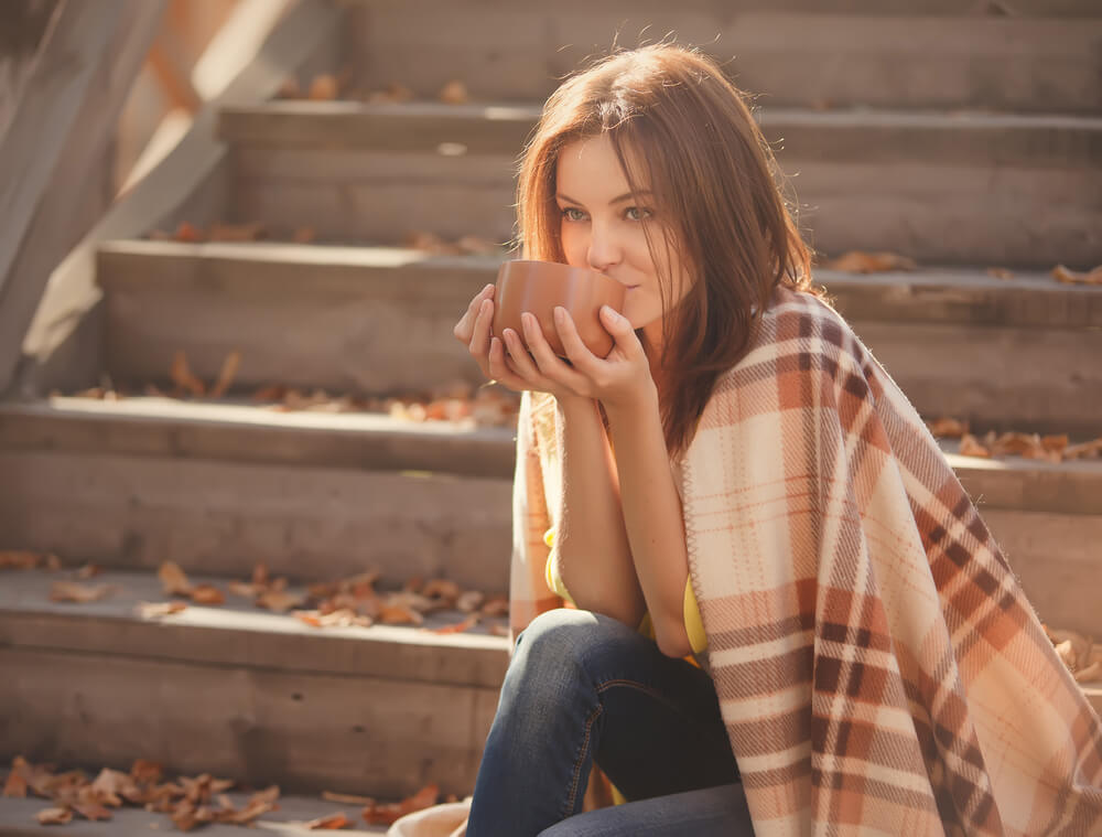 A Libra woman stays warm outdoors with a cozy blanket.