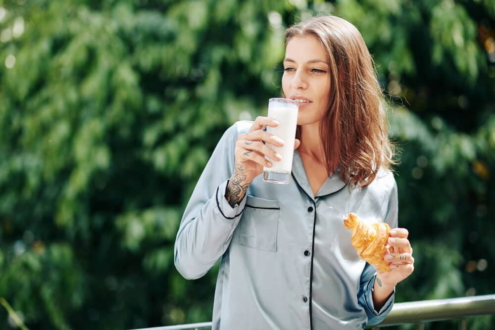 A woman eats breakfast outdoors on her birthday in her pajamas.