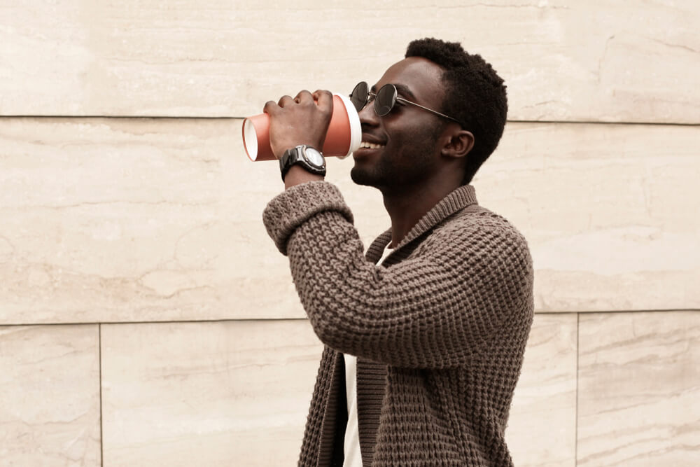 A Libra man wears a stylish sweater to get a cup of coffee.