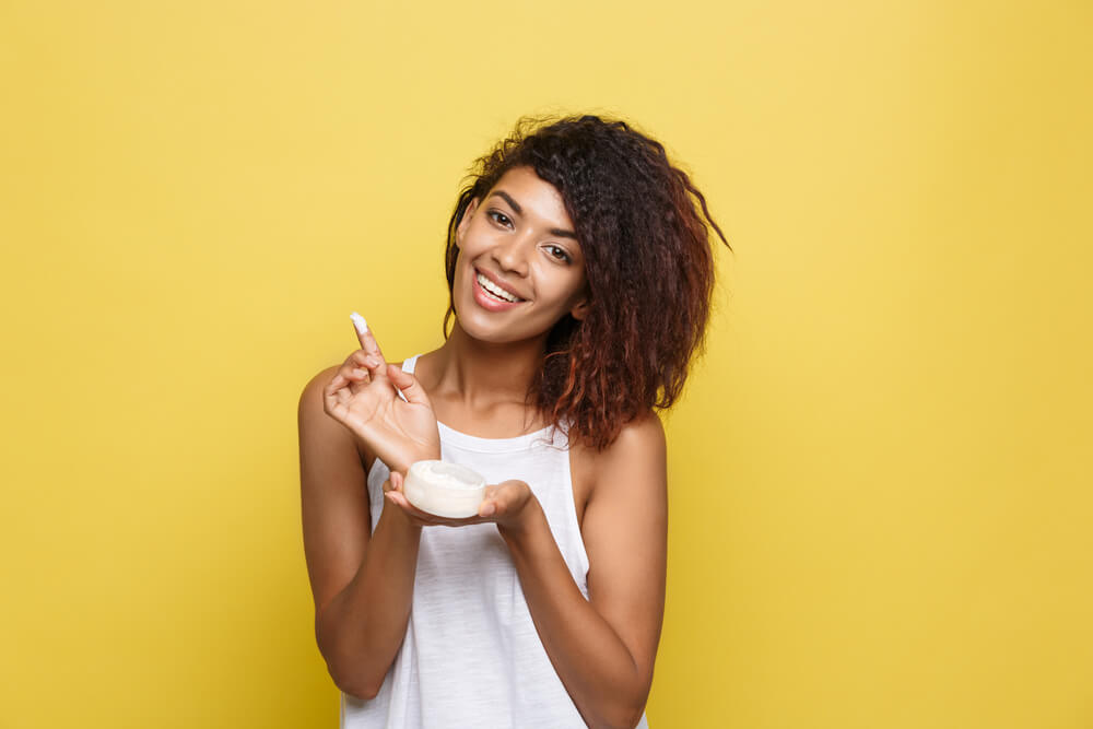 African American woman happy using skin care cream