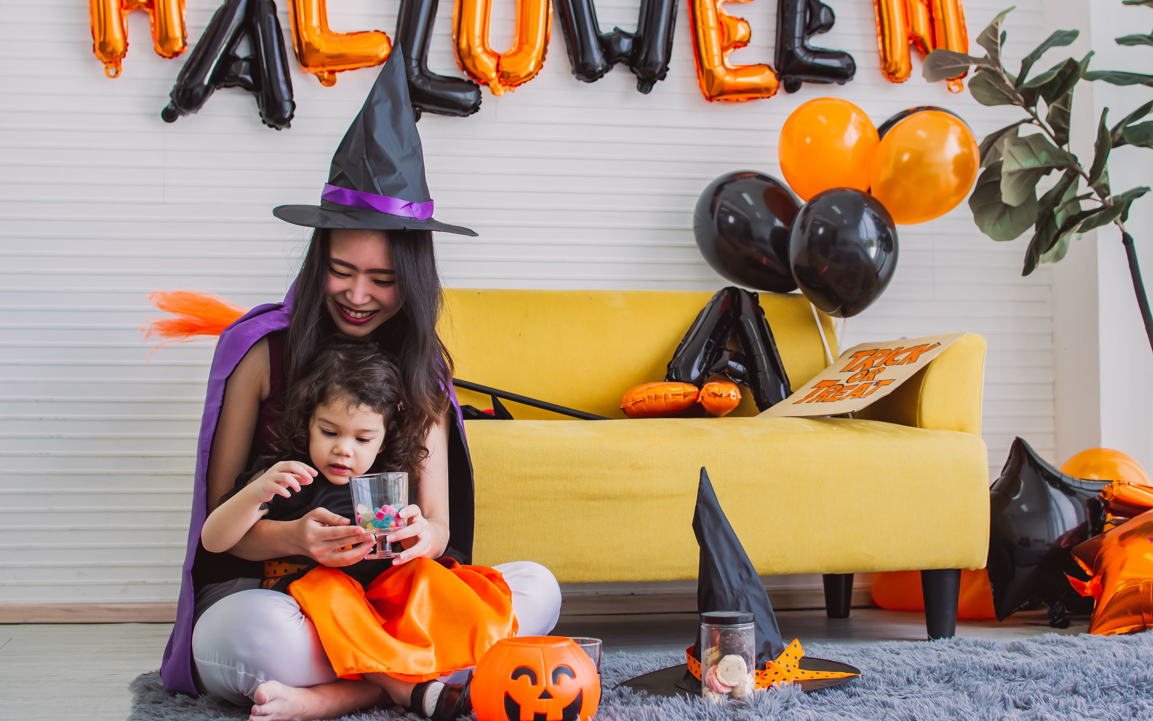 A young mom and her small daughter celebrate Halloween in cute costumes