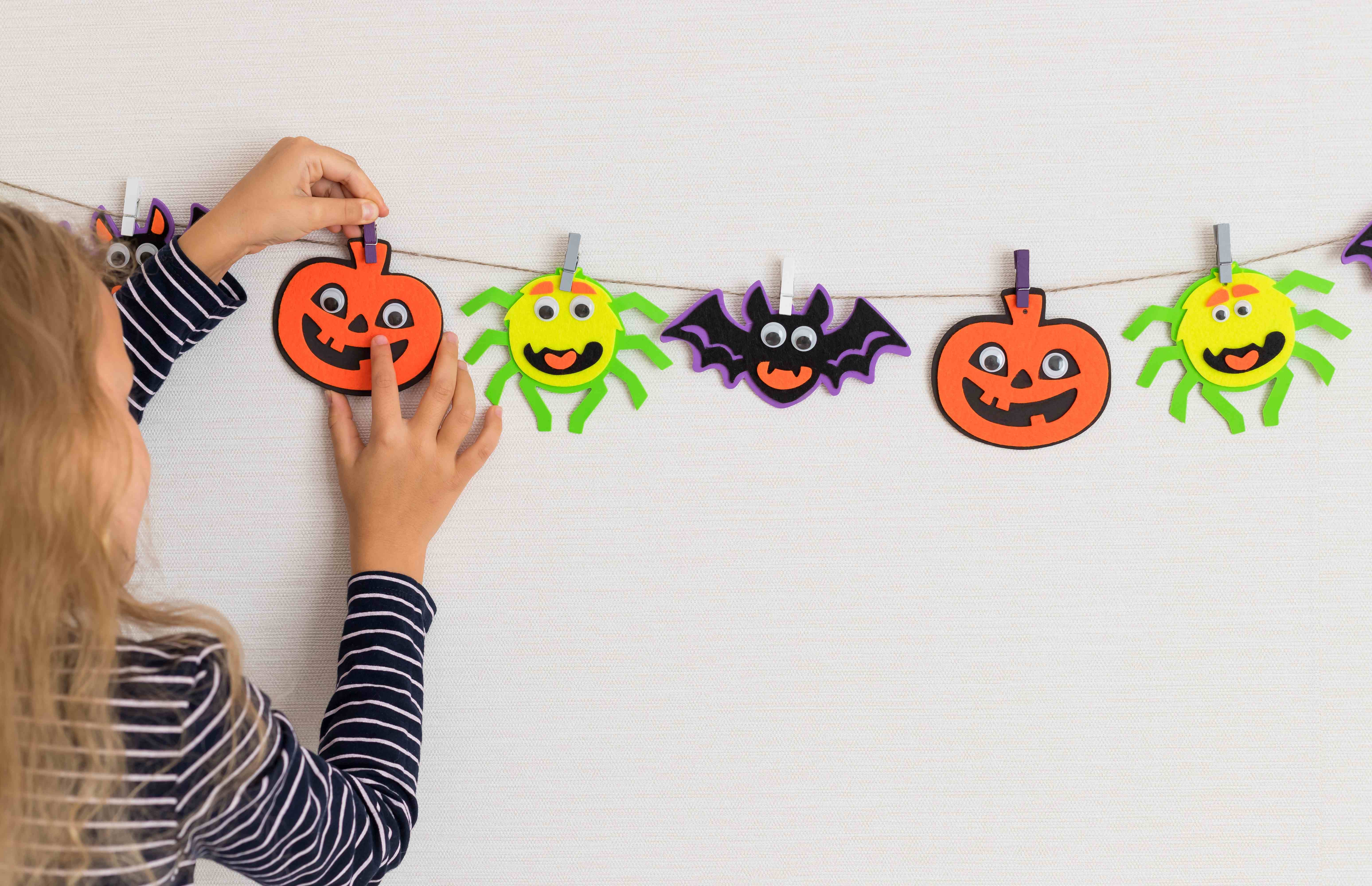 A little girl puts up family-friendly DIY Halloween decorations at home