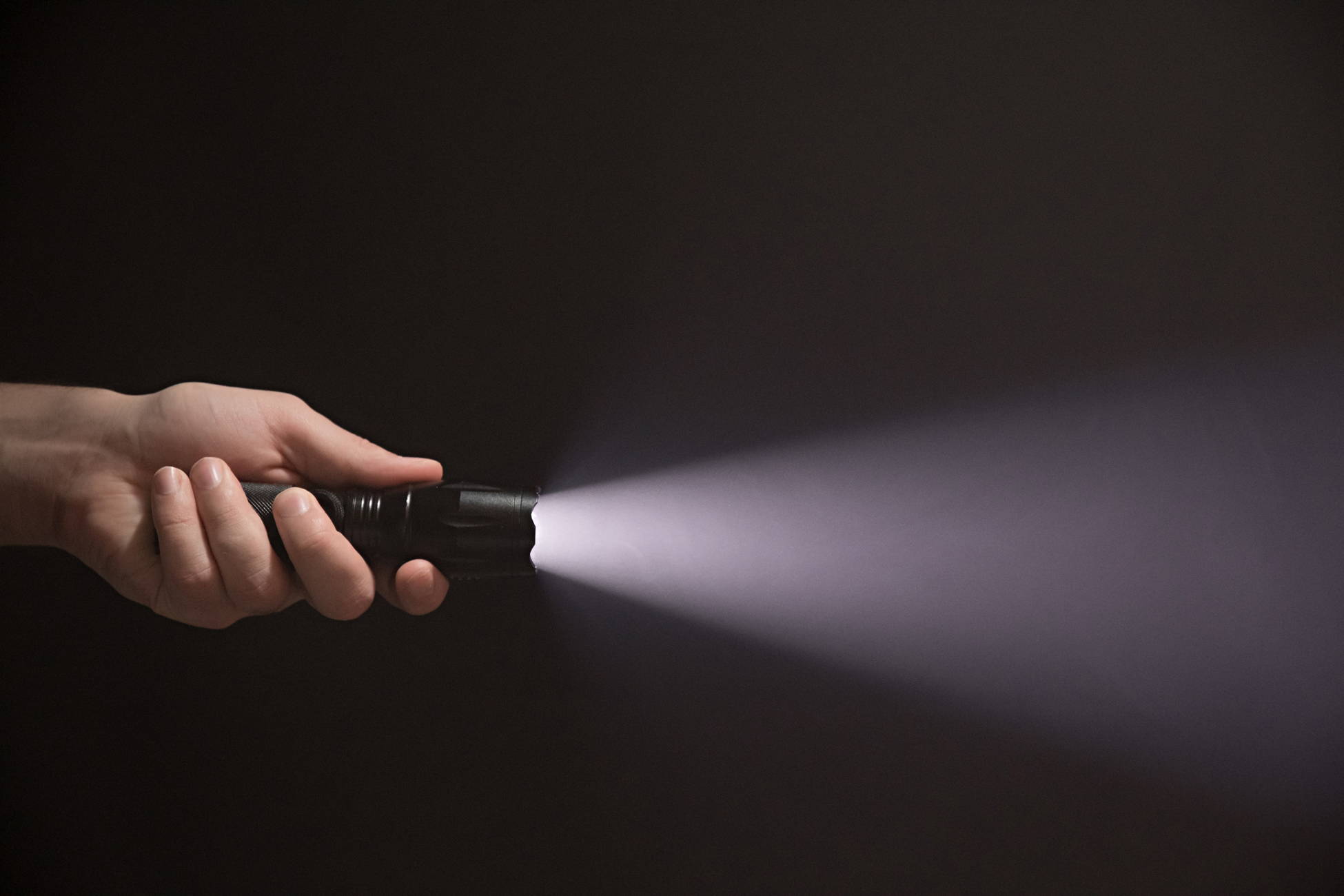 A man shines his flashlight into the dark during a power outage.