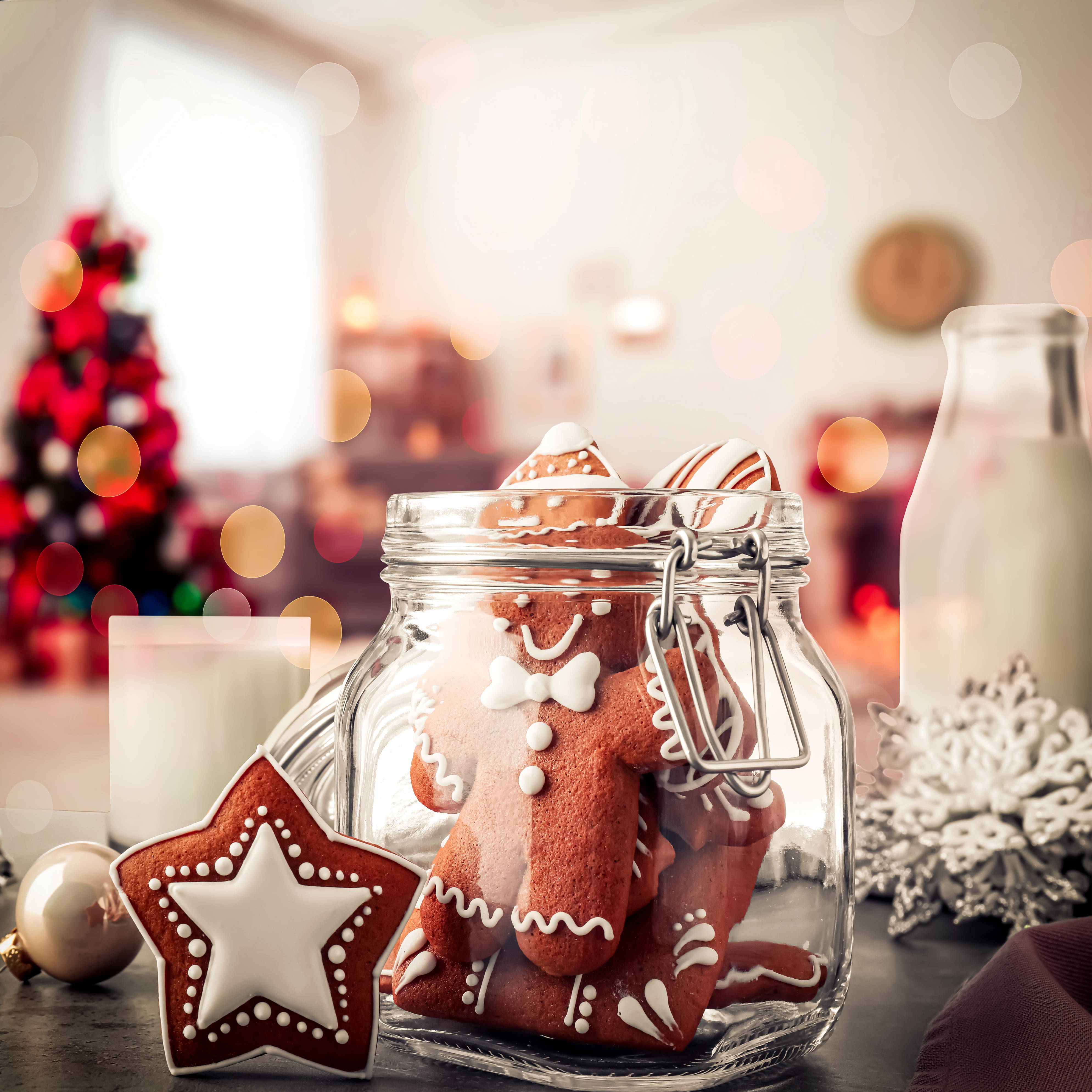 A glass jar filled with iced gingerbread cookies for the holidays.