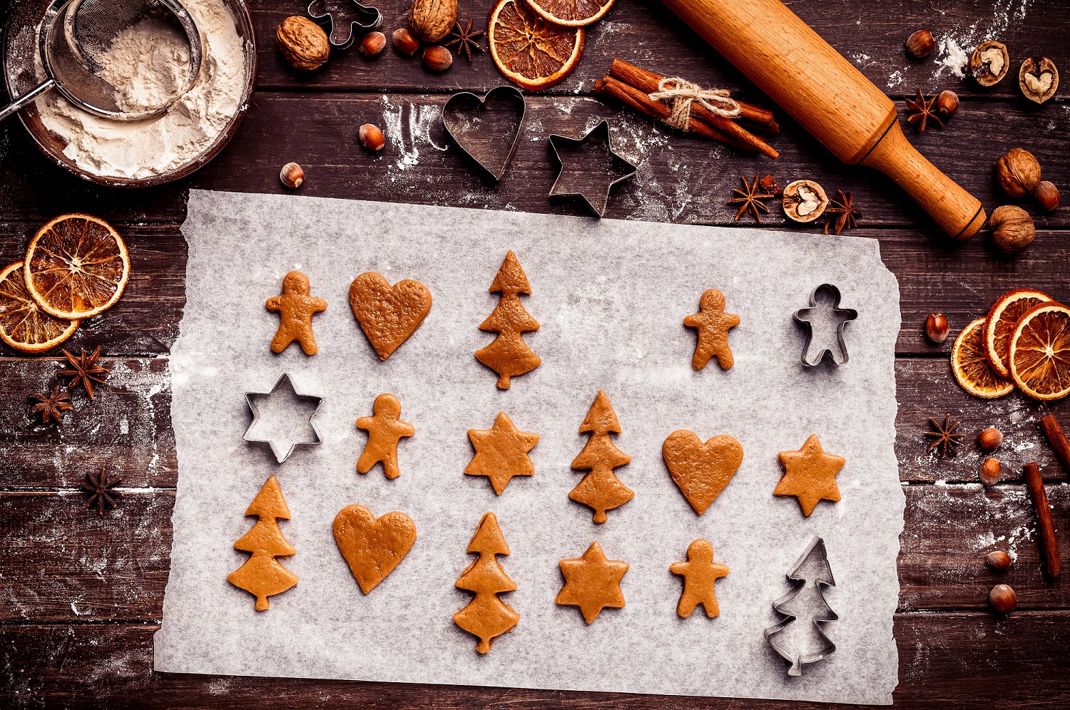 Gingerbread dough cut into festive shapes with holiday cookie cutters.