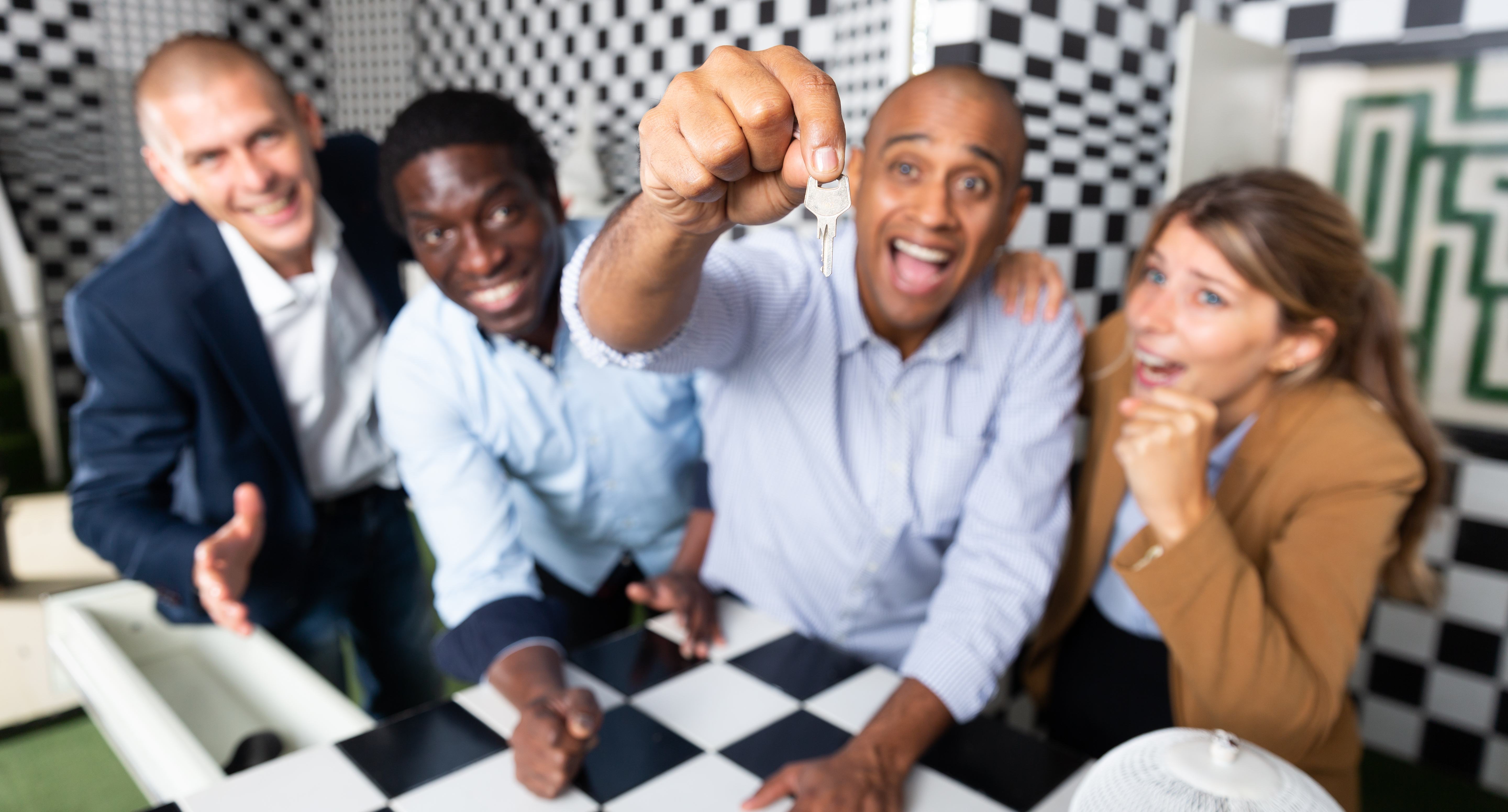 A man is excited to find an important key at an escape room with his friends. 