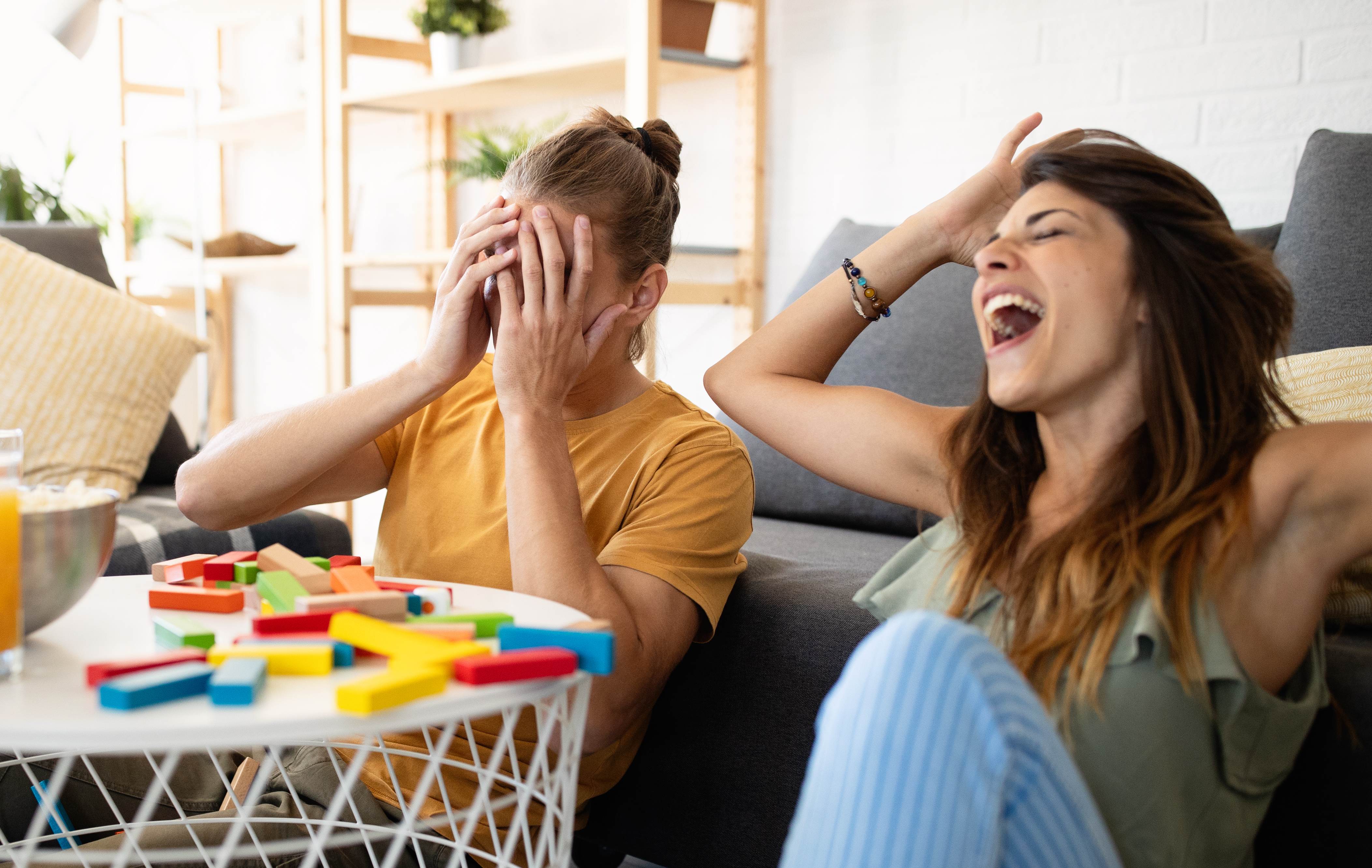 An elated woman wins at game night against her boyfriend. 