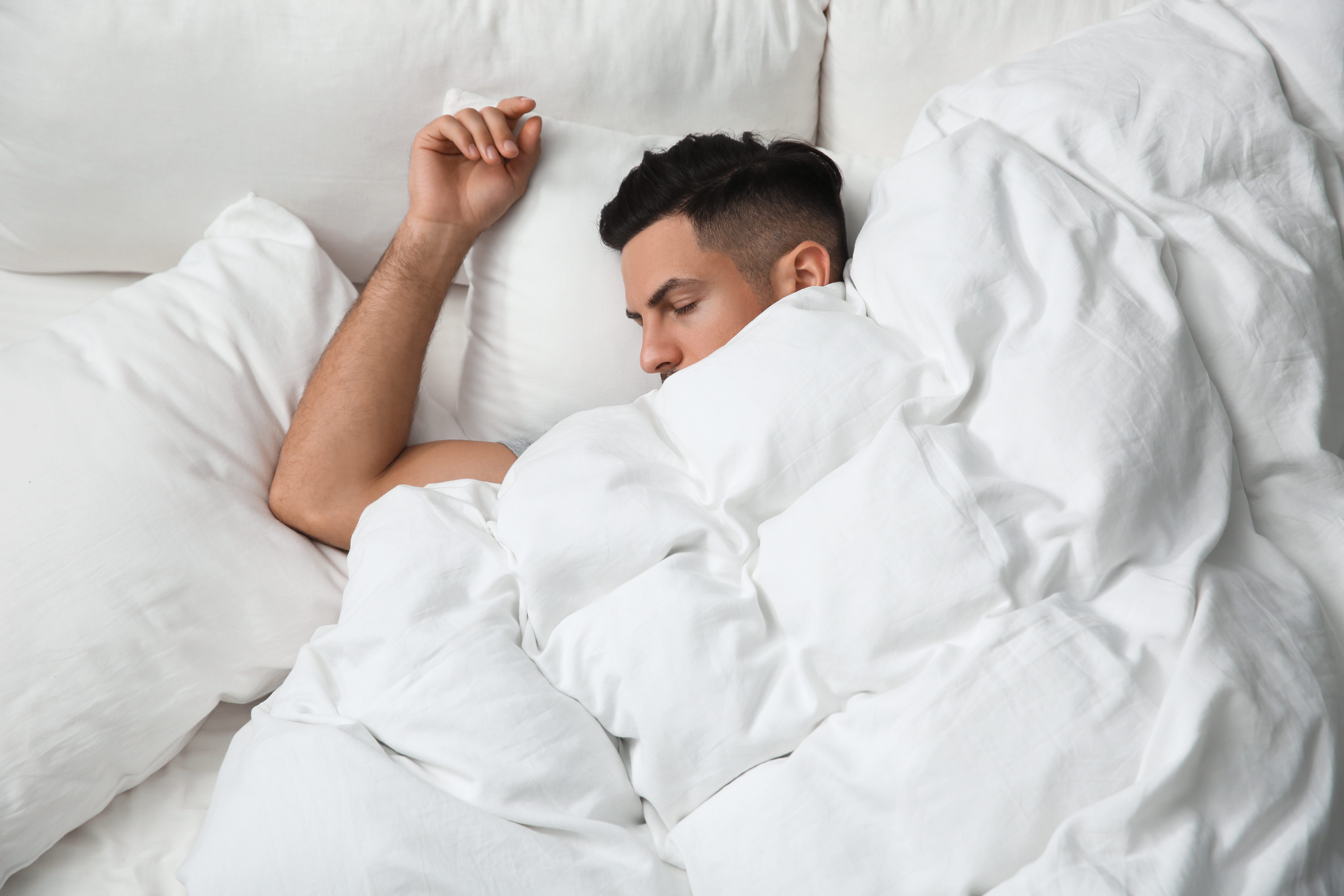 A hardworking man relaxes under the warmth of a heated blanket. 