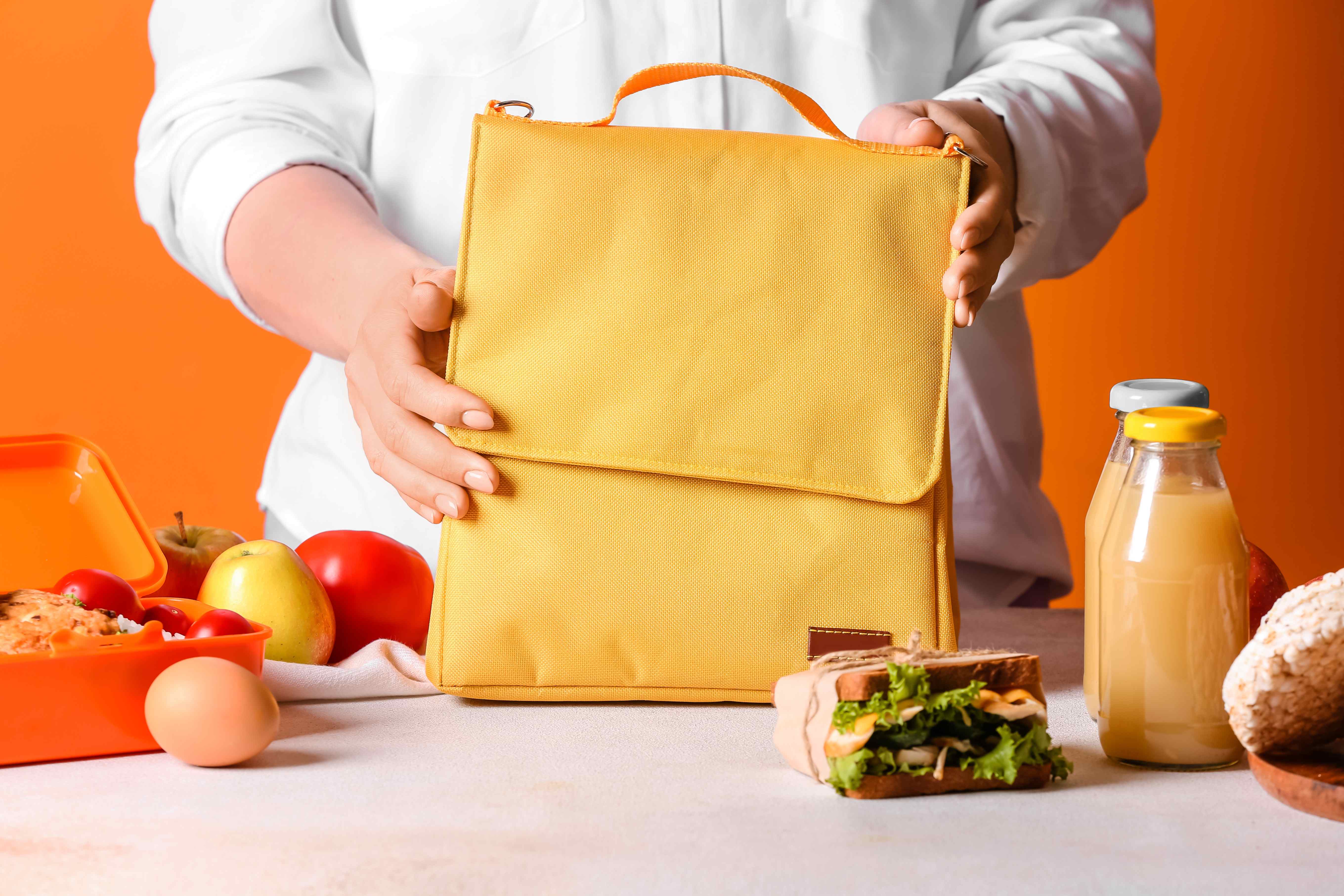 A woman packs herself a healthy meal for work in a stylish yellow lunch bag.