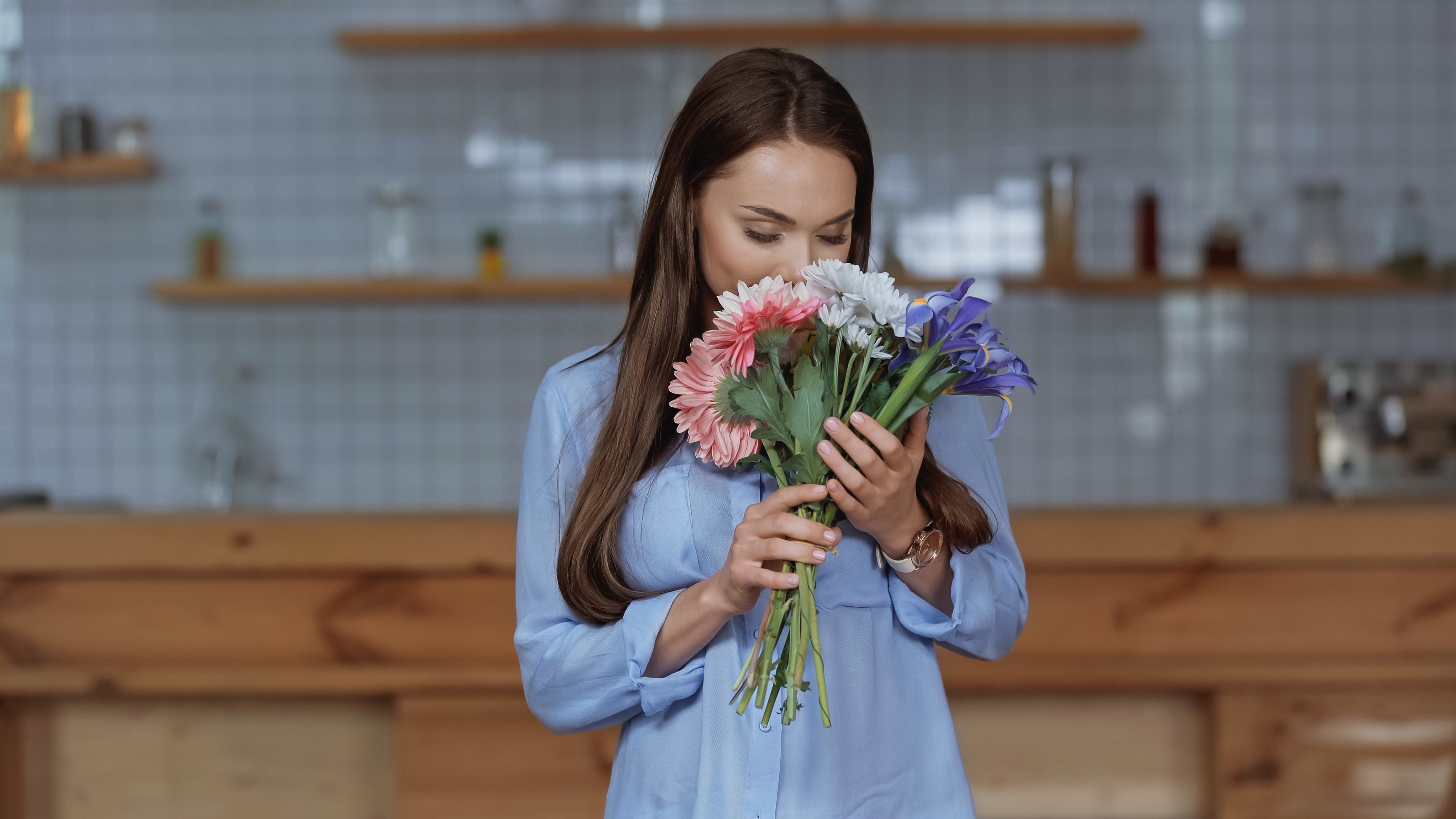 A single woman smells a bouquet of fresh flowers she sent to herself.
